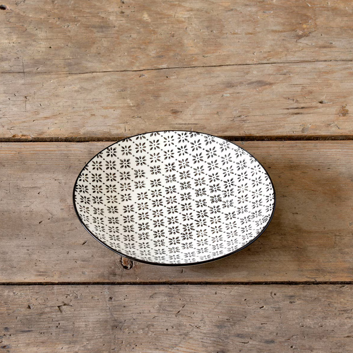 Round black & white ceramic plate with black floral pattern on a wooden surface
