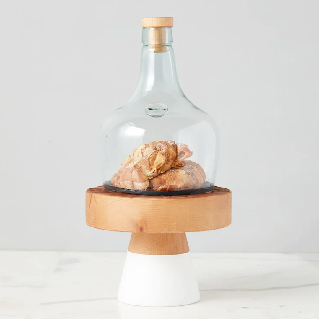 Glass cloche with wooden base and lid on a white background