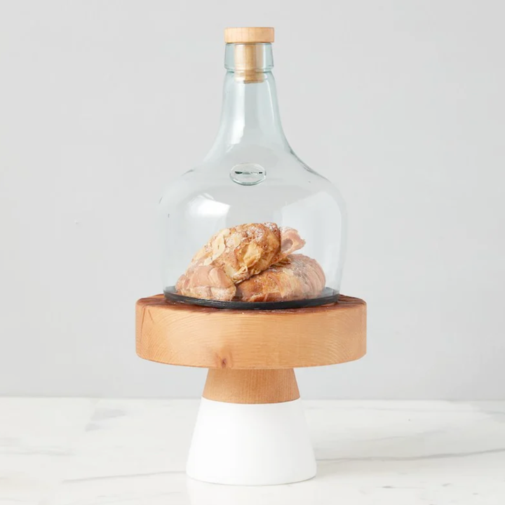 Glass cloche with wooden base and lid on a white background