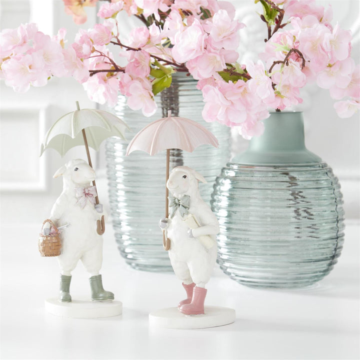 Decorative scene with rabbit figurines holding umbrellas, green frosted vases, and cherry blossoms.