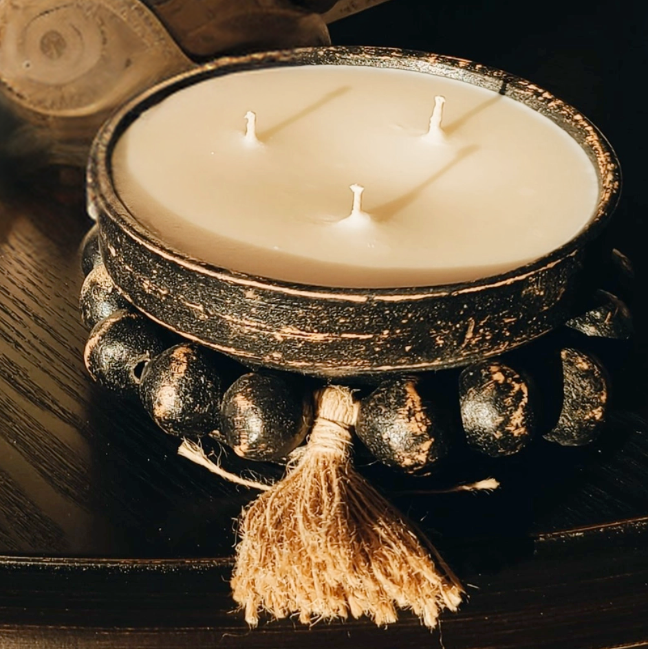 A Blueberry Pumpkin Scented Pottery Candle with a removable beaded tassel, placed on a wooden surface.