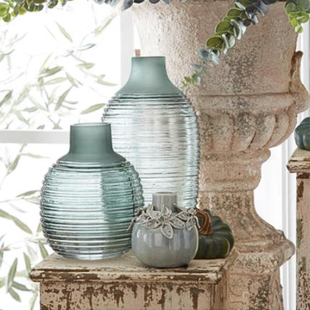 A set of two frosted sage green ribbed glass vases with a ribbed texture, displayed in a home decor setting.