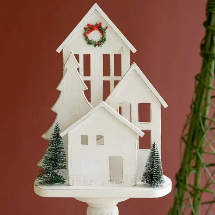 Decorative white house with Christmas trees and wreath on a red background