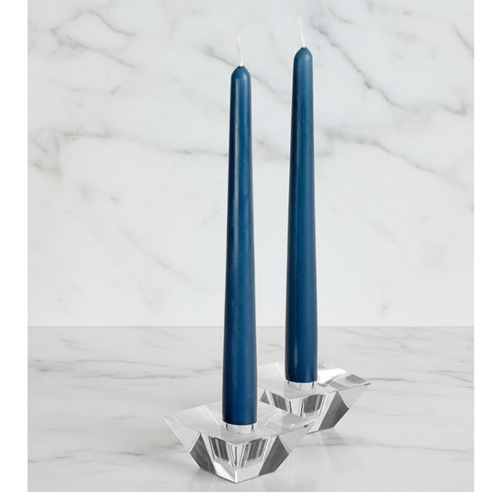 Two blue candles in a crystal candle holder on a marble surface