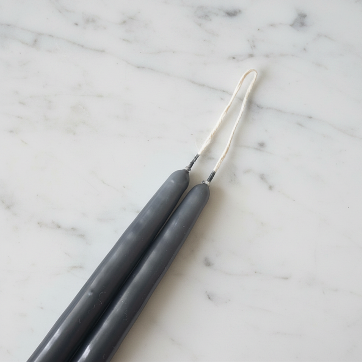12-inch charcoal gray taper candle pair against a white marble background.