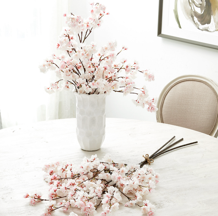 White vase with pink artificial flowers on a white tablecloth