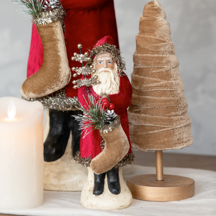 Decorative Christmas scene with Santa Claus figure, stockings, and small tree.
