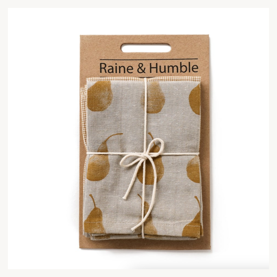 A set of two folded Duchess Pear tea towels with a gold and cream mini check pattern, tied together with a string on a cardboard backing, labeled 'Raine & Humble'.