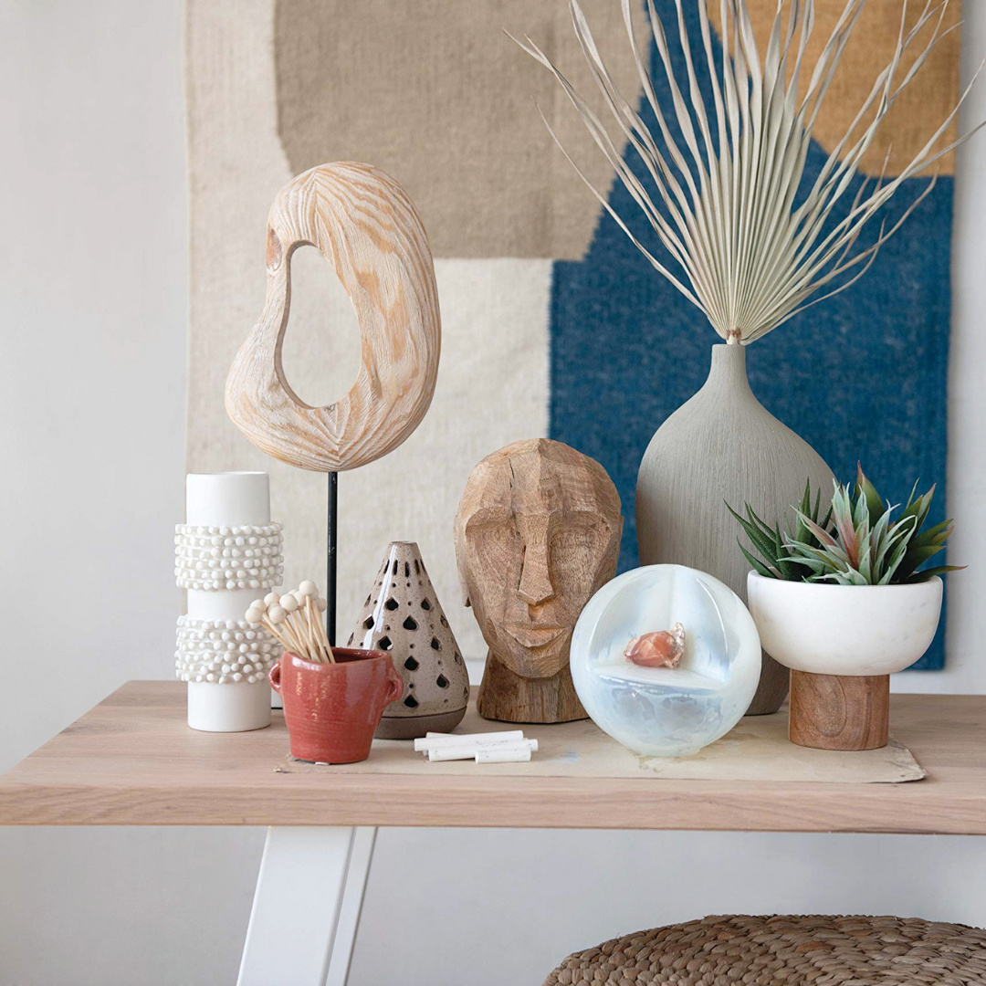 Decorative items on a wooden shelf with a abstract wall art in the background