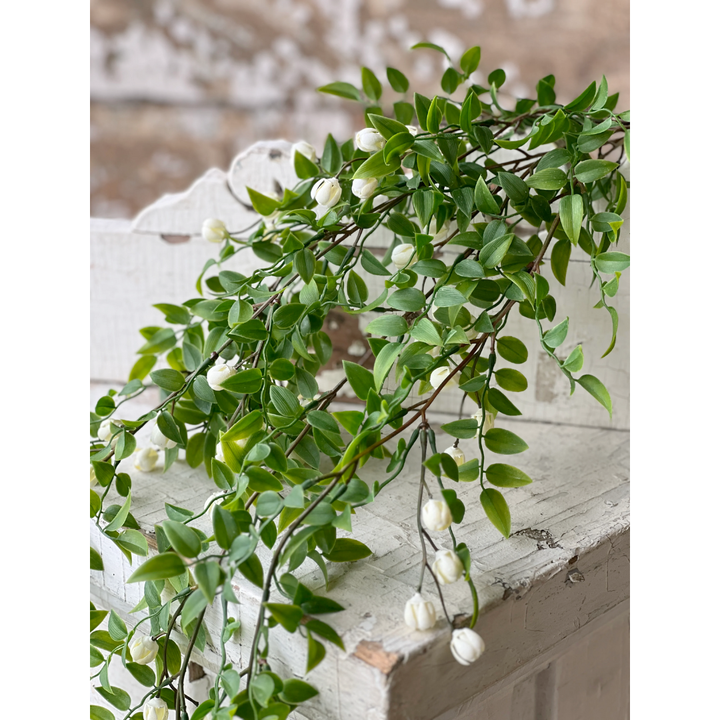 Artificial green vine with white flowers on a wooden surface