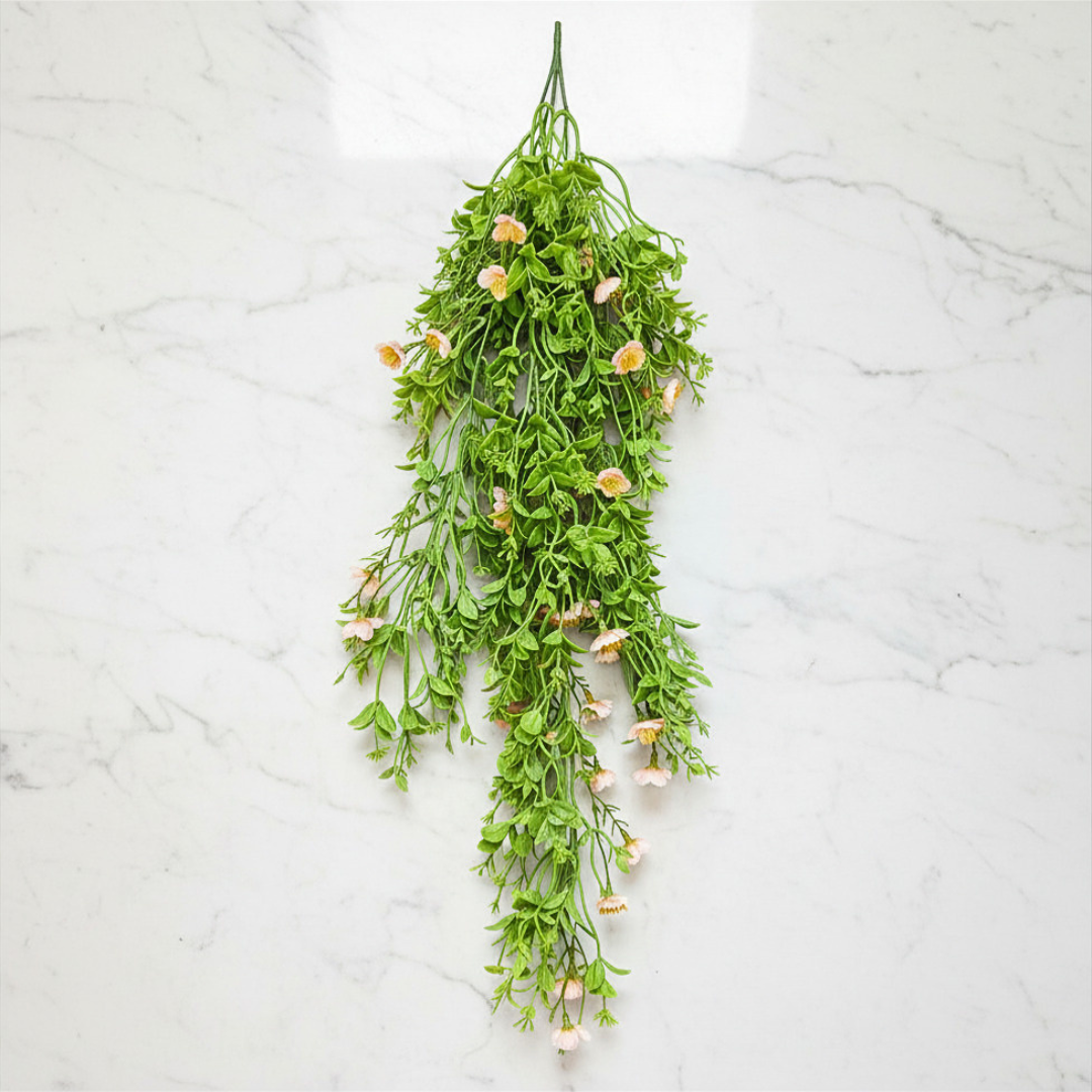 Hanging green plant with small flowers on a white marble background