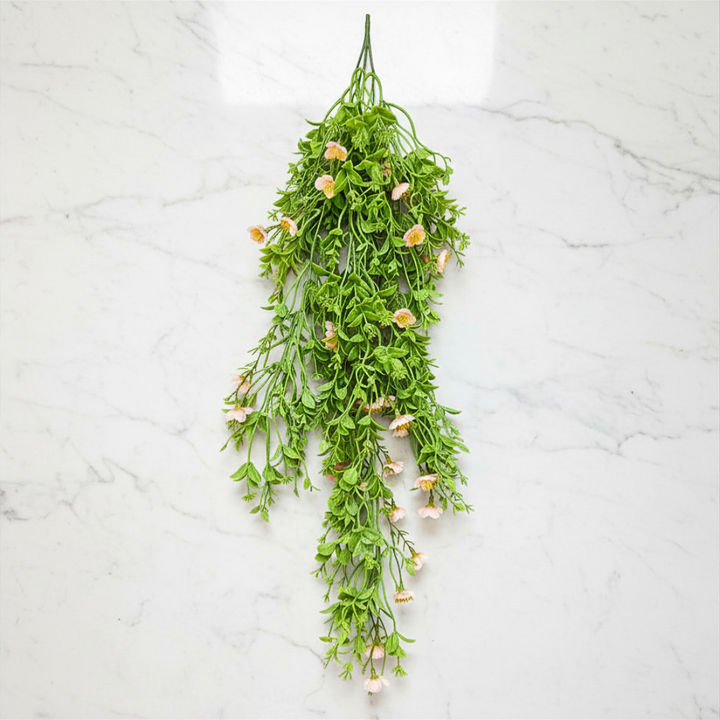 Hanging green plant with small flowers on a white marble background
