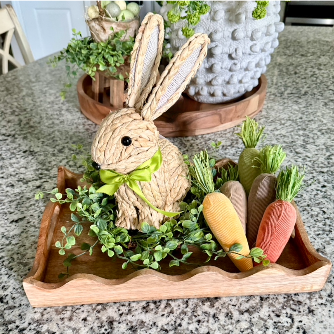 Decorative tray with a woven bunny, carrots, and greenery on a countertop.