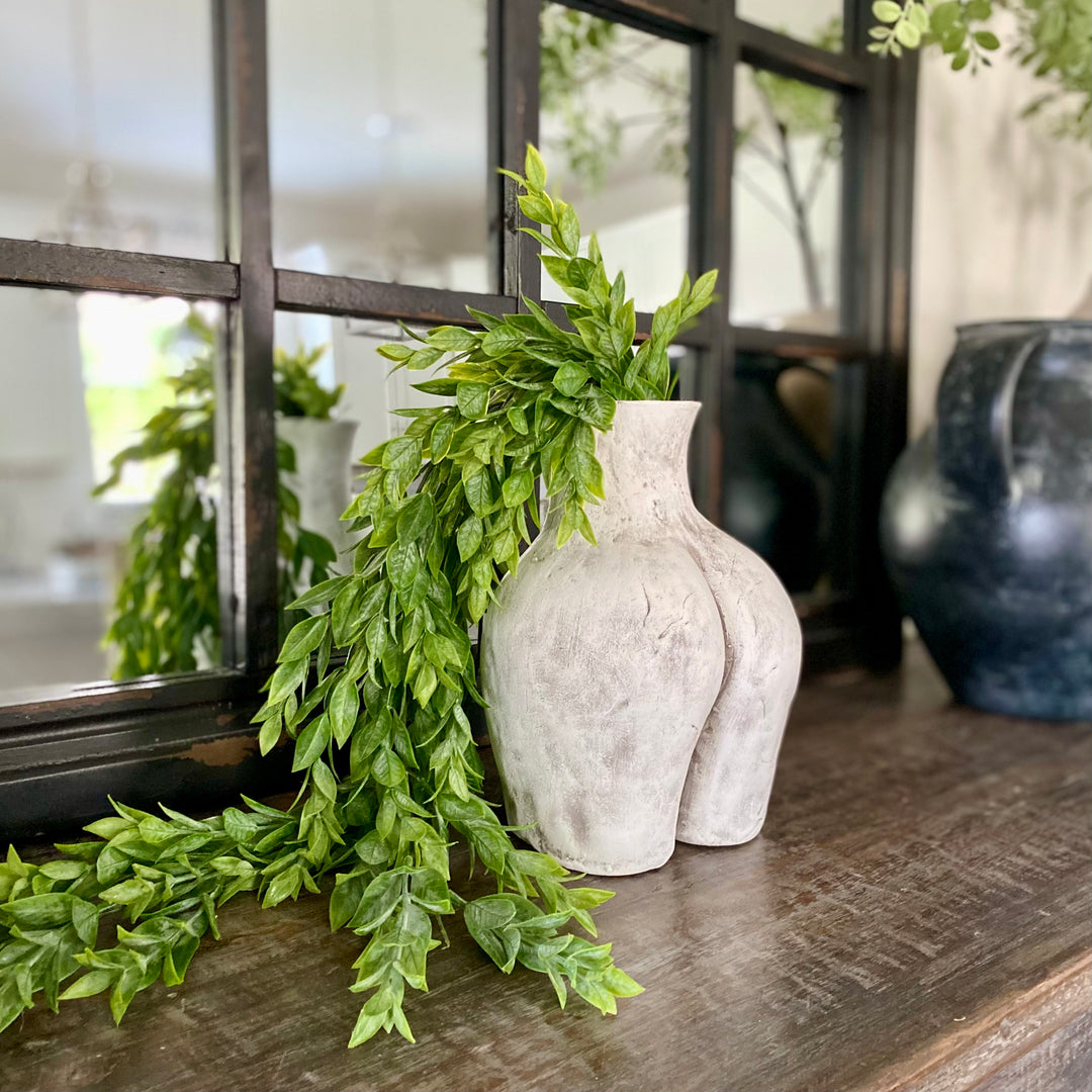Handcrafted  Clay Culo Pot with greenery in front of a windowpane mirror