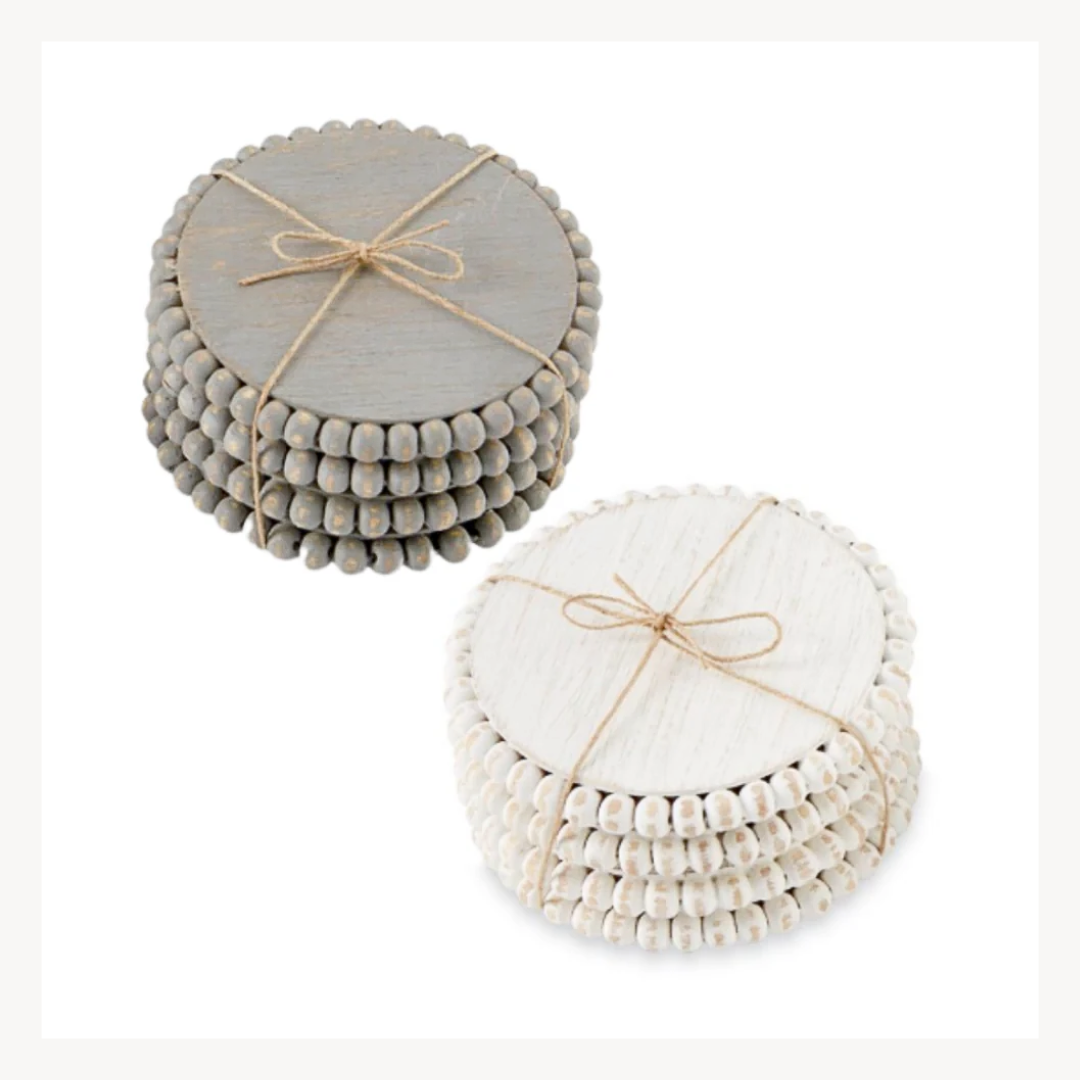 Two sets of beaded wood coasters in gray and white, tied with twine and stacked.