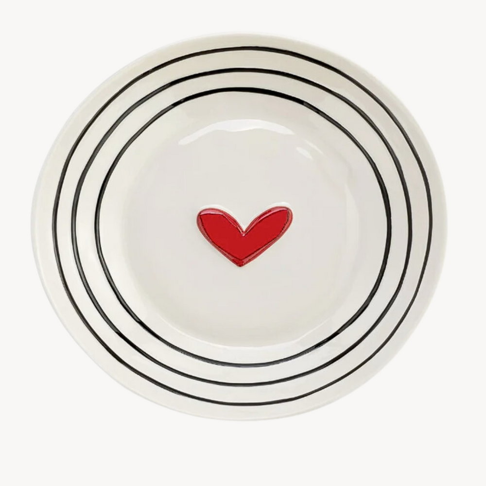 A white stoneware serving bowl with black dots pattern and a red heart in the center.