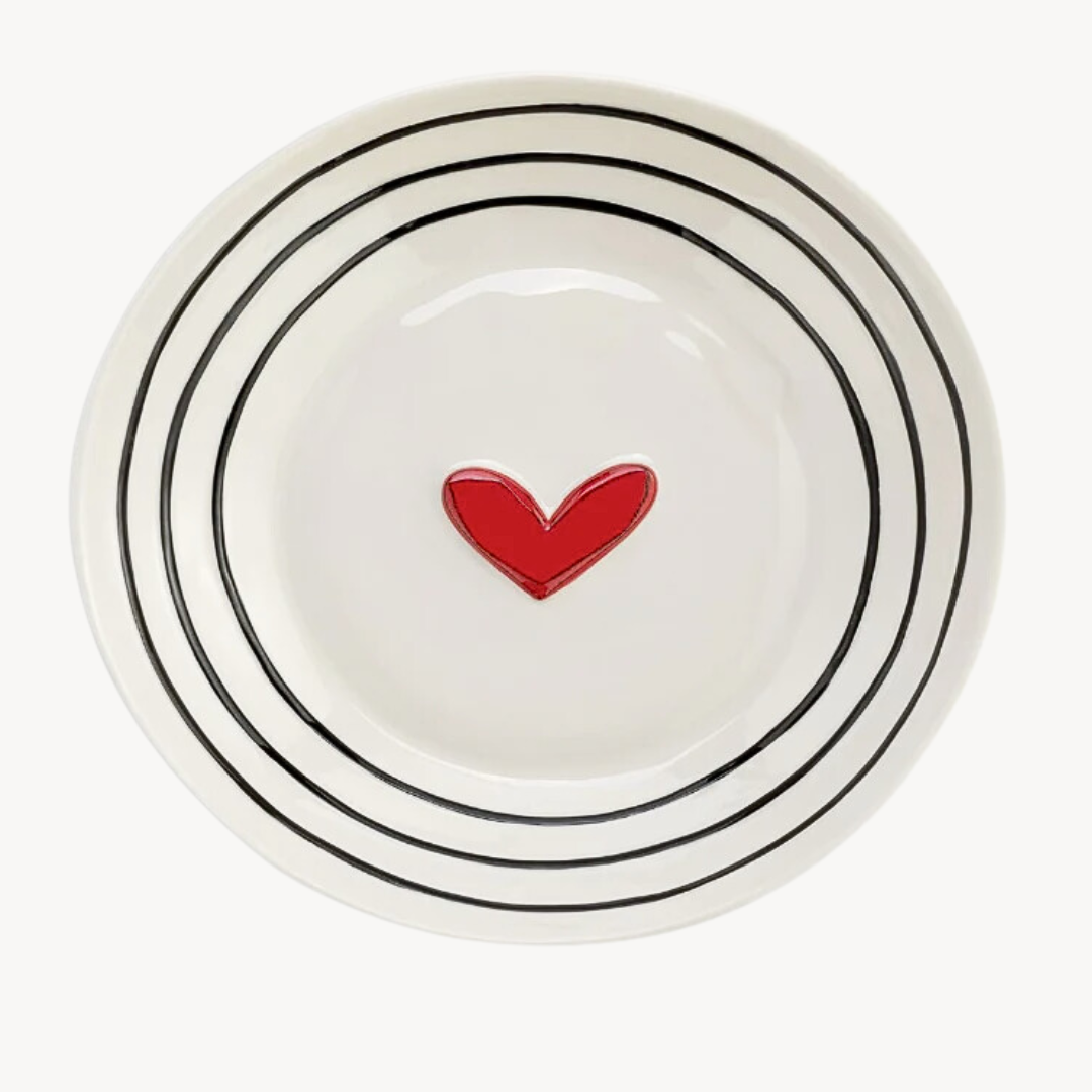 A white stoneware serving bowl with black dots pattern and a red heart in the center.