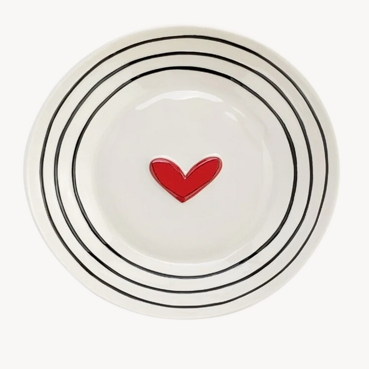 A white stoneware serving bowl with black dots pattern and a red heart in the center.