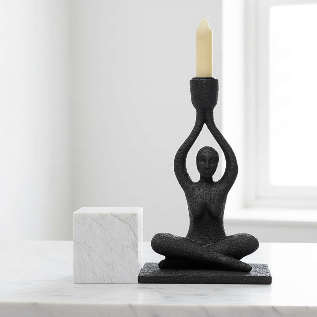 Black abstract candle holder in the shape of a person on a marble surface with a white background