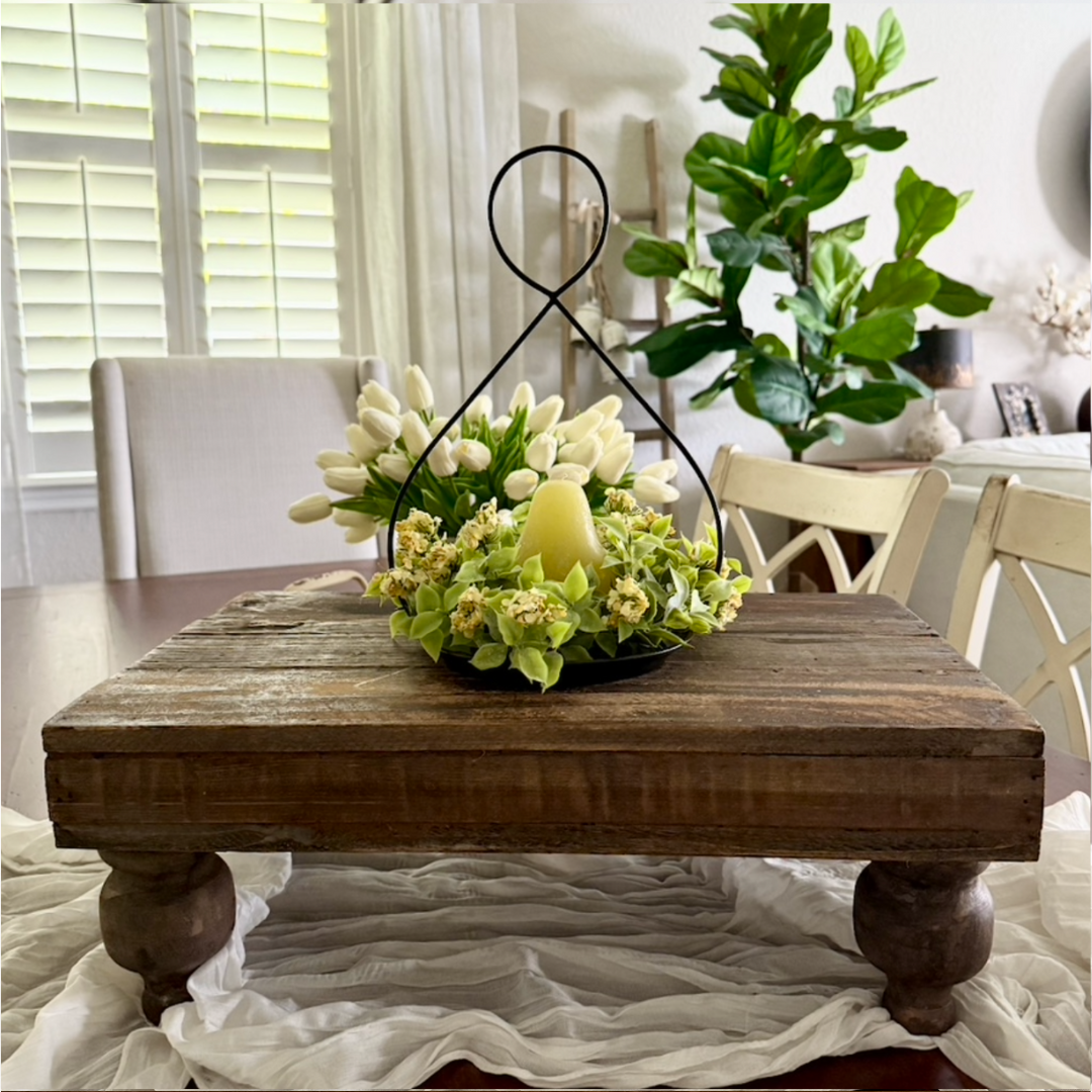 Decorative floral arrangement with a candle on a wooden table in a home setting