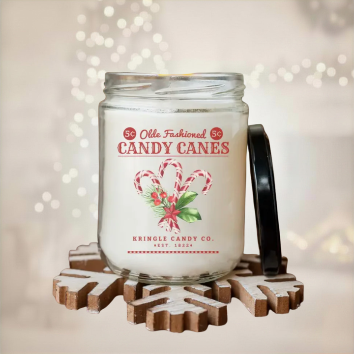 Candle in a jar with a candy cane design label on a decorative stand with a blurred light background