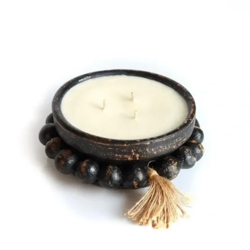 Candle in a decorative wooden holder with a tassel on a white background