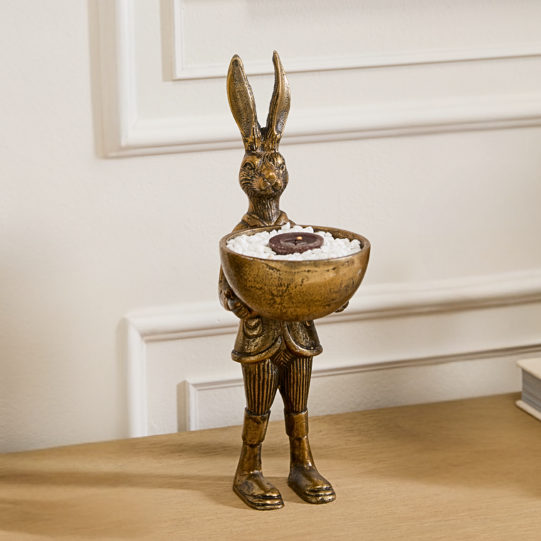 A brass figurine of a rabbit standing upright holding a bowl, with an antiqued gold finish.