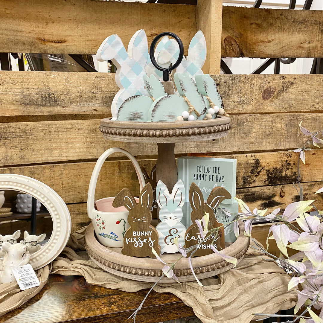 Decorative items including bunny-shaped candles and signs on a wooden surface.