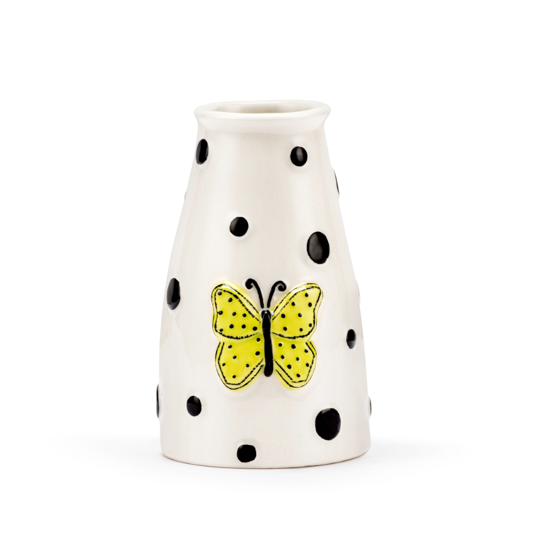 White vase with black polka dots and a yellow butterfly design on a white background