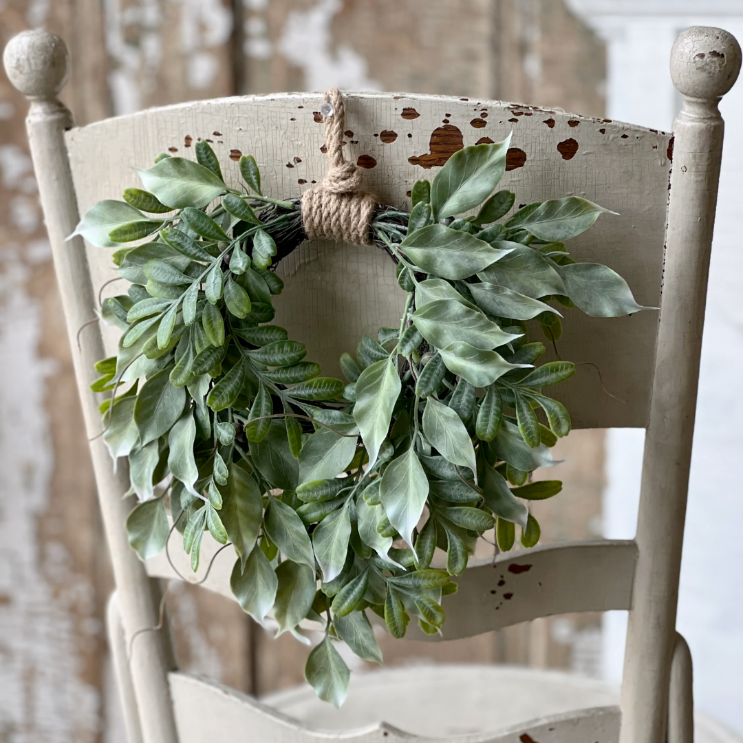 Green leaf wreath on a rustic wooden chair with a blurred background