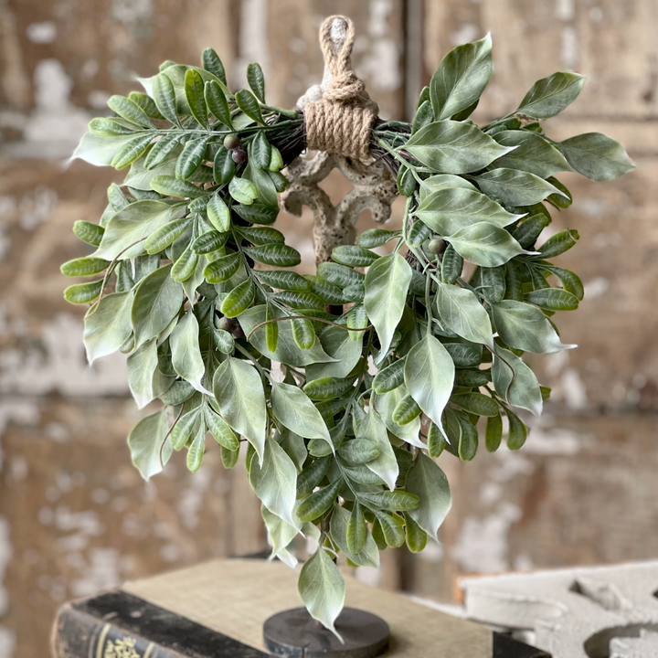 Green leafy wreath on a rustic wooden stand with a textured background