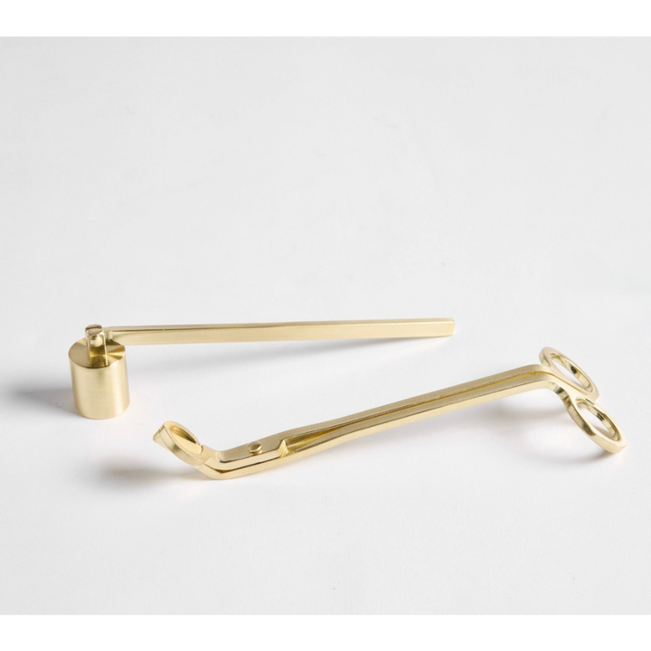 Gold-colored candle trimmer and candle snuffer on a light gray background