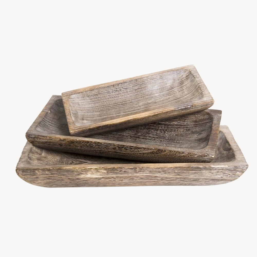 A set of three carved wooden trays in varying sizes with a rustic finish, stacked on top of each other.