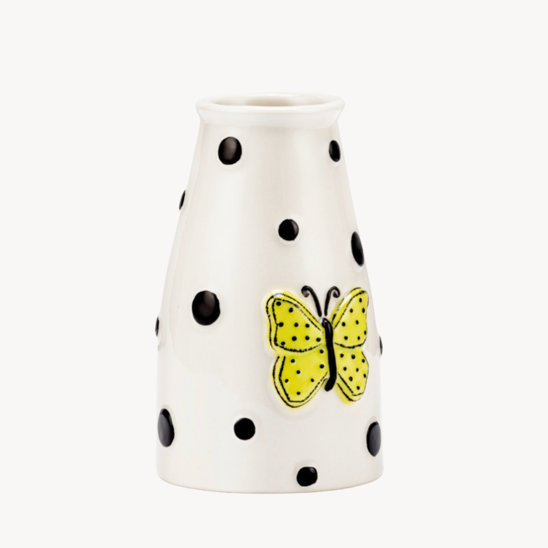 A white ceramic mini vase with black dots and a bright yellow-green butterfly design on the side.