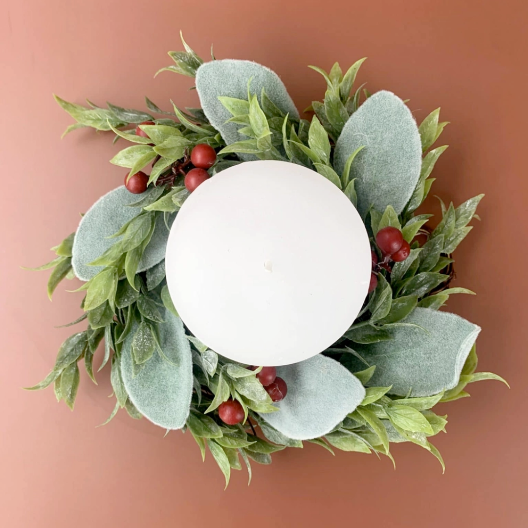 Decorative wreath with green leaves and red berries on a plain background