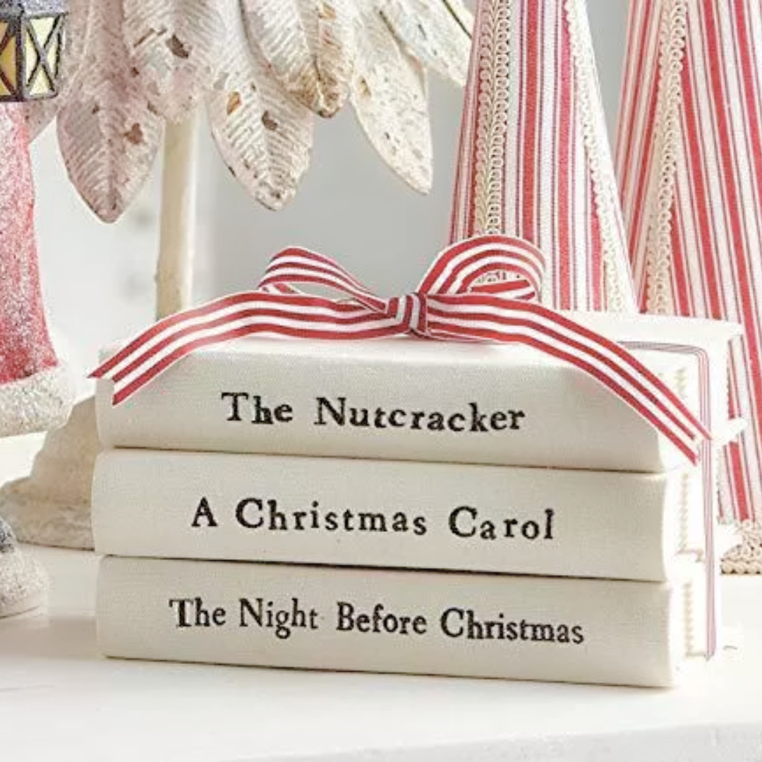 A stack of cream-colored books with red stripes and a red ribbon, featuring titles such as 'The Nutcracker', 'A Christmas Carol', and 'The Night Before Christmas'.
