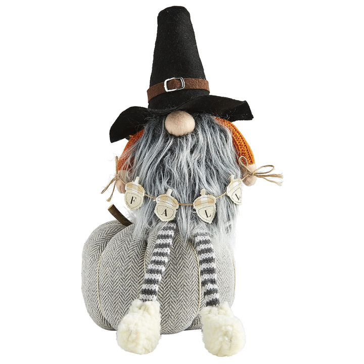 A decorative autumn gnome doll with a tall black hat, gray beard, orange knit accents, striped legs, and white pom-pom feet, photographed on a plain white background.
