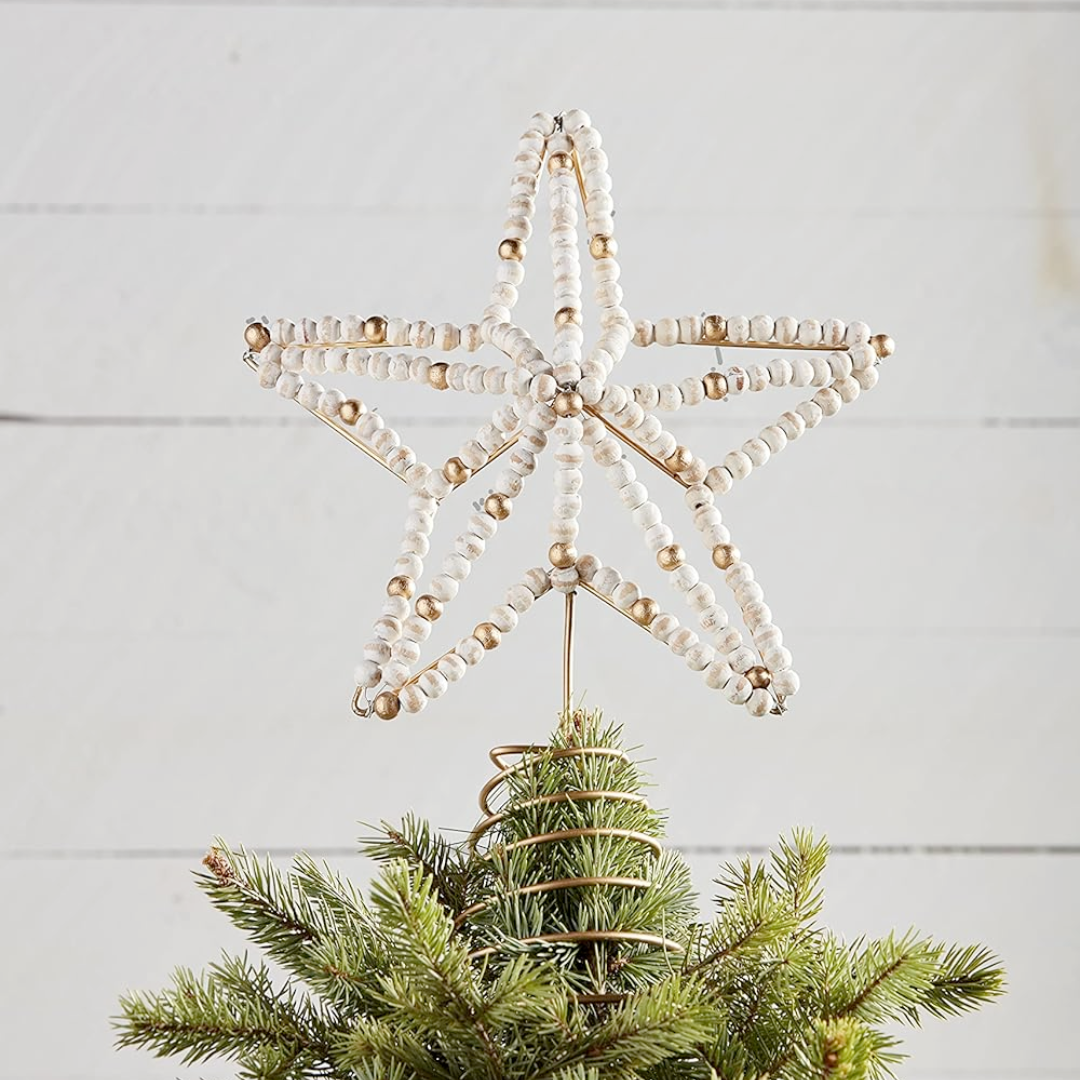 Decorative star tree topper with beads on a Christmas tree against a light wooden background