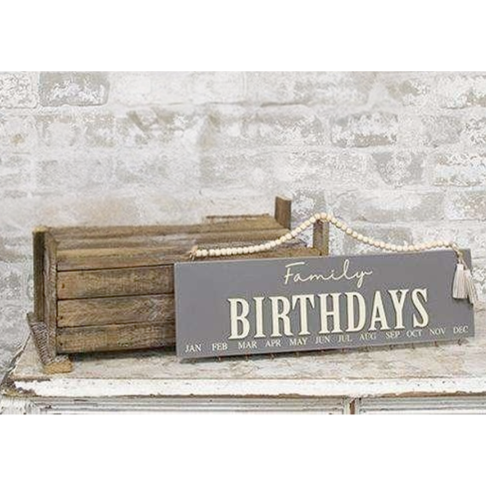 Wooden crate with a decorative sign reading 'Family Birthdays' against a stone wall background.