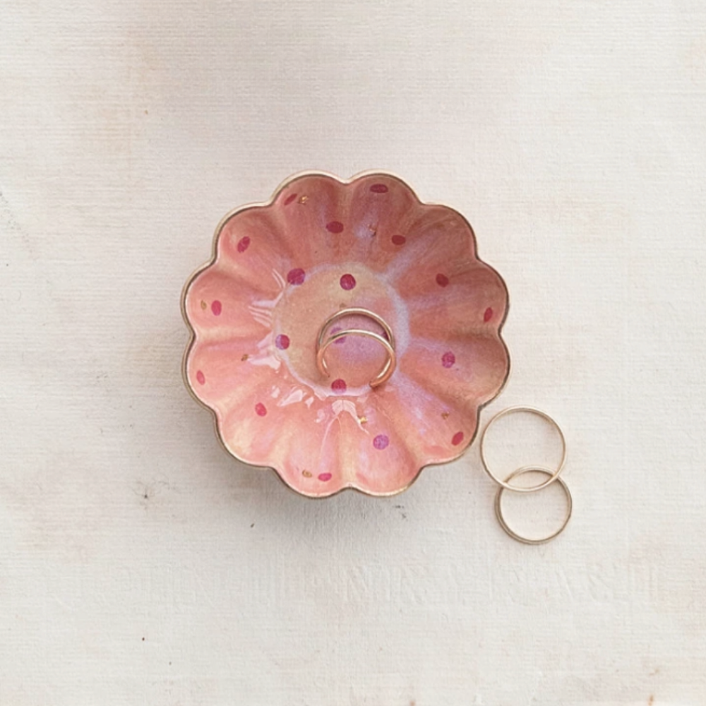 Pink floral ring holder with rings on a light beige background