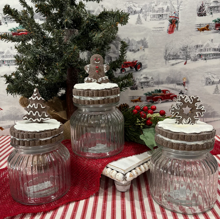 Decorative glass jars with gingerbread men on a tablecloth with a Christmas-themed background
