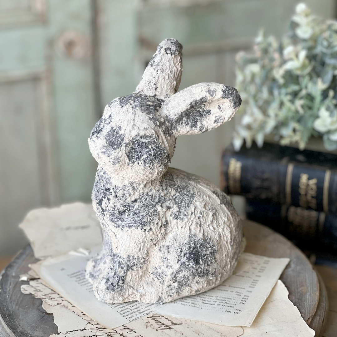 Decorative stone rabbit figurine on a surface with books and papers