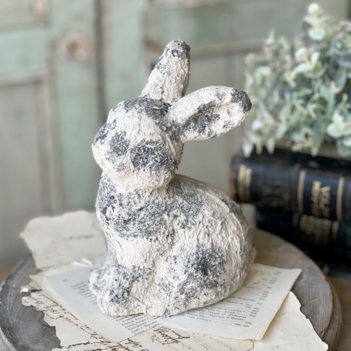 Decorative stone rabbit figurine on a surface with books and papers