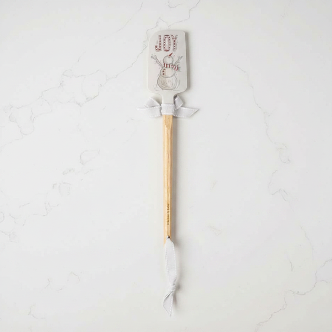 Spatula with wooden handle and silicone head on a light gray background
