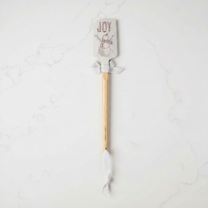 Spatula with wooden handle and silicone head on a light gray background