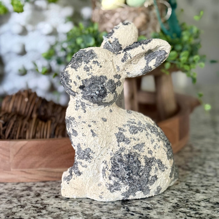 Decorative paper pulp rabbit figurine on a marble surface with plants in the background