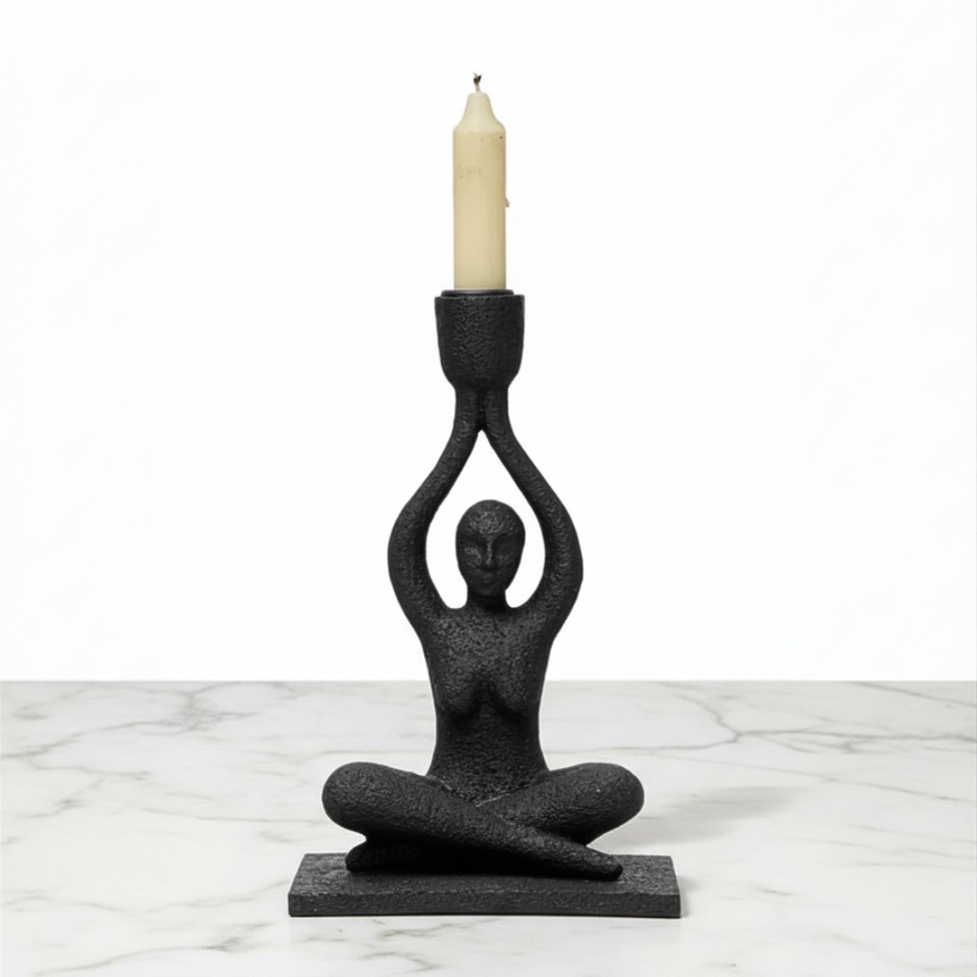 Black candle holder shaped like a person holding a candle on a marble surface