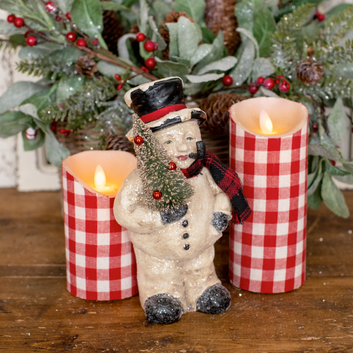Decorative snowman figurine with candles and Christmas decorations on a wooden surface