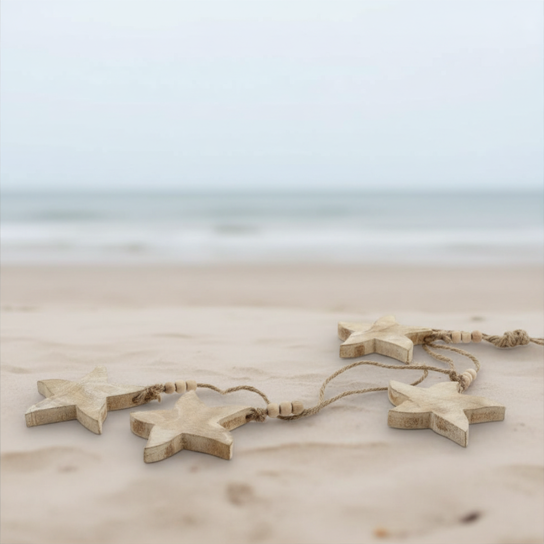 Star-shaped wooden decorations on a sandy beach with a blurred ocean background