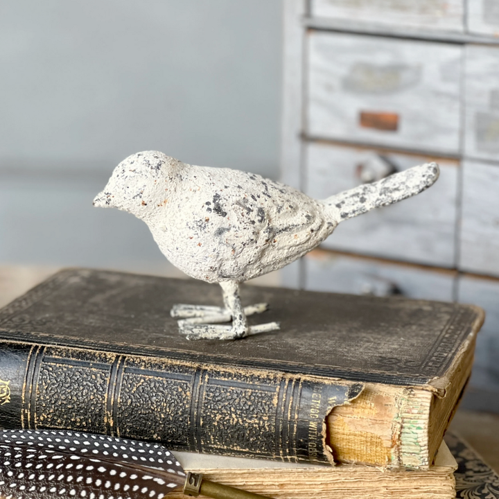 Decorative bird figurine on top of vintage books with a blurred background